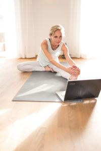 Woman 40+ practices yoga at home with notebook. Online yoga class. Woman 40+ practices yoga at home with notebook. Online yoga class.